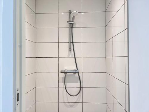 a shower with a hose on a white tiled wall at Three Bedroom Apartment In Valby, Valby Langgade 214, in Copenhagen