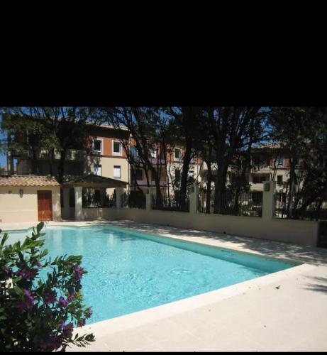 une grande piscine bleue devant un immeuble dans l'établissement Chez Louis de Uzès, à Uzès