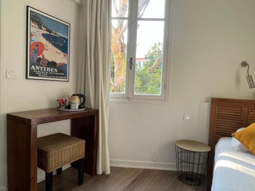 a bedroom with a bed and a table and a window at Hotel Alexandra - Boutique Hotel in Juan-les-Pins