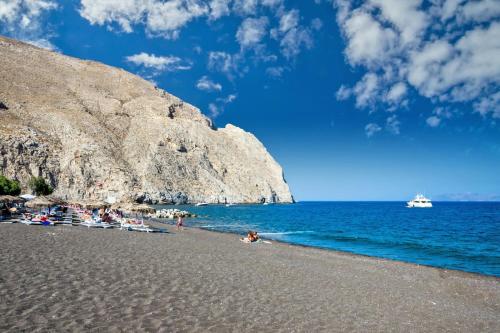 un grupo de personas en una playa cerca del agua en Santorini Seaside Retreat - Flora's Summer Escape en Perissa