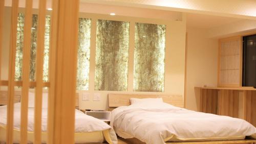 a bedroom with two beds and two windows at こんぴら温泉湯元八千代 in Kotohira