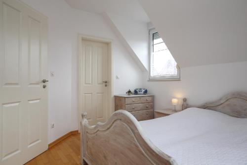 a white bedroom with a bed and a window at Sanddornweg Wohnung 13 a in Boltenhagen