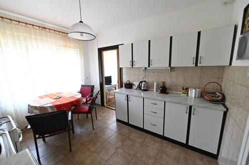 une cuisine avec des placards blancs et une table avec des chaises dans l'établissement Apartment Aby, à Zagreb
