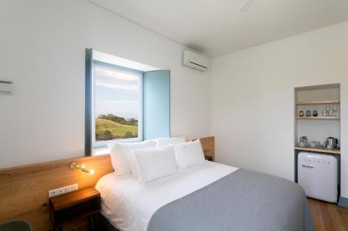 a bedroom with a bed with a large window at Solar Branco Eco Estate in Ponta Delgada