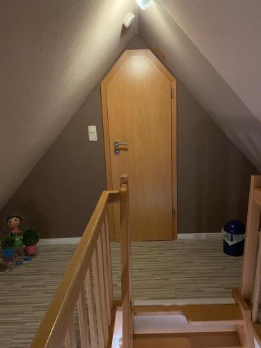 a staircase with a wooden door in a attic at Ferienwohnung Halen Landkreis Cloppenburg in Halen