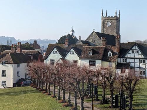 un grupo de casas con una torre de reloj y árboles en Cosy character cottage in central Marlborough UK en Marlborough