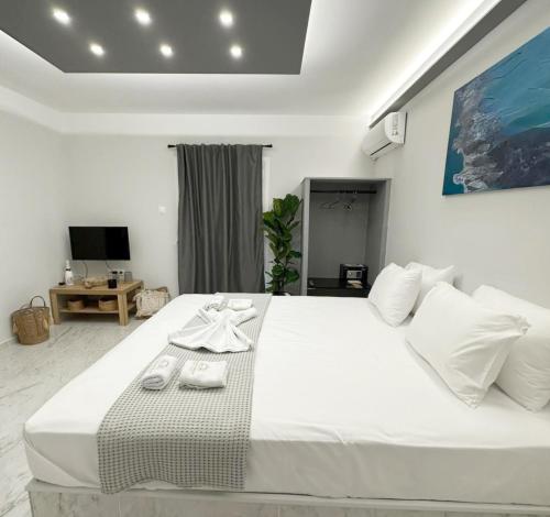 a bedroom with a large white bed with towels on it at Mora Houses in Mandrakia