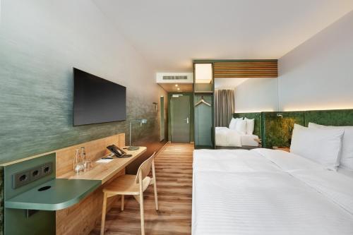 a hotel room with a large bed and a desk at H+ Hotel Frankfurt Eschborn in Eschborn