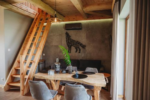 a room with a wooden table and chairs and a ladder at OSADA LEŚNA - domki z basenem in Stare Miasto