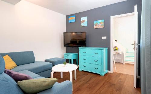 a living room with a blue couch and a tv at Stiniva Bay - Hvar Villa in Brusje