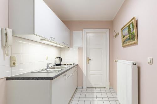 una pequeña cocina con armarios blancos y fregadero en Villa Seebach, en Boltenhagen