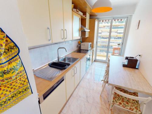 La cuisine est équipée de placards blancs, d'un évier et d'un comptoir. dans l'établissement Spacieux 2P climatisé avec terrasses et garage, proche centre de Menton et plages - FR-1-196-332, à Menton