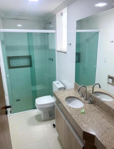 uma casa de banho com 2 lavatórios, um WC e uma cabina de duche em vidro. em Hotel Wilson em Teixeiras