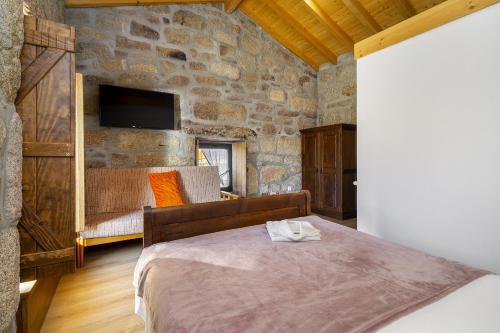 1 dormitorio con 1 cama en una habitación con una pared de piedra en Isatour -Natural Park House, en Vouzela