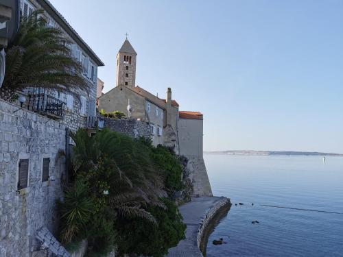a church on a hill next to a body of water at Deluxe Apartment "Sunset in Barbat" with sea view in Rab