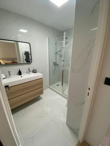 une salle de bain blanche avec un lavabo et une douche dans l'établissement T2 avec Terrasse et Jardin, à Cannes