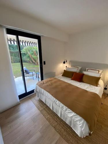 une chambre avec un grand lit et une grande fenêtre dans l'établissement T2 avec Terrasse et Jardin, à Cannes