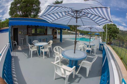 a patio with tables and chairs and an umbrella at Chácara das Araras in Lindóia