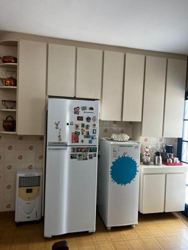 a kitchen with white cabinets and two refrigerators at Chácara das Araras in Lindóia