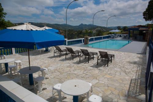 een zwembad met tafels en stoelen en een parasol bij Chácara das Araras in Lindóia