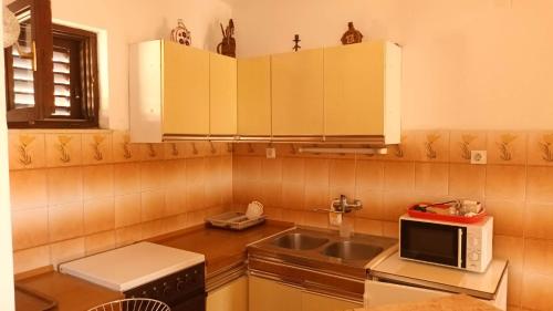 cocina con fregadero y microondas en apartmani DIMIĆ, en Supetar