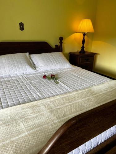 a white bed with a bouquet of flowers on it at Chácara das Araras in Lindóia