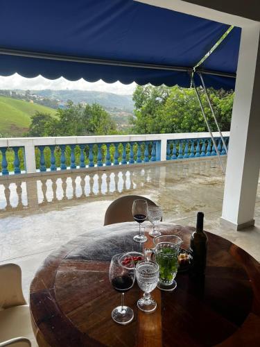 a wooden table with wine glasses on a balcony at Chácara das Araras in Lindóia
