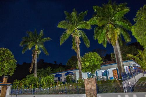 a group of palm trees in front of a house at Chácara das Araras in Lindóia