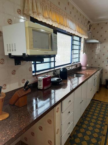 a kitchen with a counter with a microwave and a sink at Chácara das Araras in Lindóia
