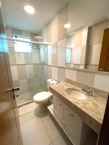 a bathroom with a toilet and a sink and a mirror at Cobertura Luxo Sophia I - Orla Praia Grande in Arraial do Cabo