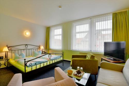 a hotel room with a bed and a tv at Hotel Goldene Sonne in Arnstadt