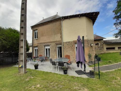 ein Haus mit einem Tisch, Stühlen und einem Sonnenschirm in der Unterkunft Gite d'ardin in Vrigne-aux-Bois