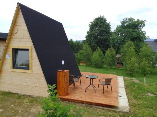 uma pequena casa com um telhado preto e um deque de madeira em Szałas, Namiot w Górach Izerskich, agroturystyka, ogrzewanie, klimatyzacja , plac zabaw, ognisko z rusztem i kijkami, żywe zwierzęta, latem basen em Mirsk