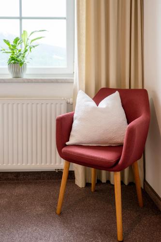a red chair with a white pillow in a room at Wawies Apartments in Flachau