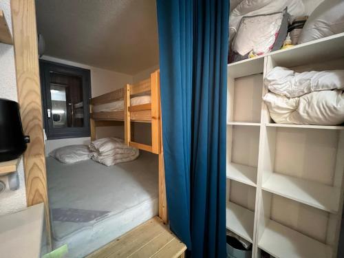 une petite chambre avec des lits superposés et un rideau bleu dans l'établissement Grand Sud, à La Salle Les Alpes