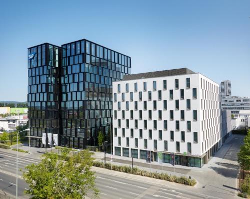 two tall buildings in a city with a street at H+ Hotel Frankfurt Eschborn in Eschborn