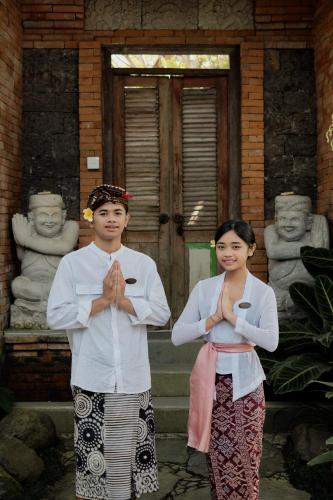 two people standing in front of a house with their hands in front at Roshan Ubud Villa in Ubud