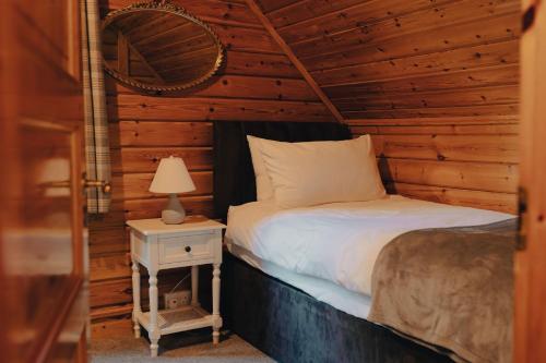 um quarto com uma cama e uma mesa de cabeceira com um candeeiro em Pines Pitch em Bleddfa