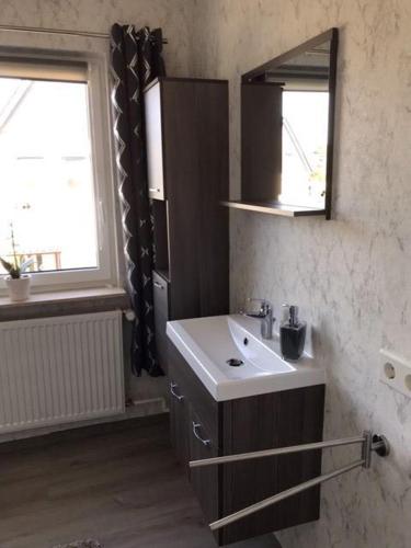 een badkamer met een wastafel, een spiegel en een raam bij Kathrin, Ferienwohnung in Schneverdingen
