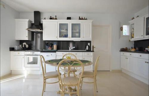 a kitchen with white cabinets and a table and chairs at L'Hacienda, Haut de villa de deux chambres, avec salle de bain et toilettes WC privative in Fréjus