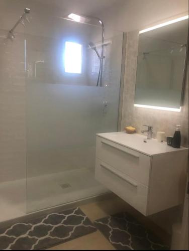 a white bathroom with a sink and a shower at L'Hacienda, Haut de villa de deux chambres, avec salle de bain et toilettes WC privative in Fréjus