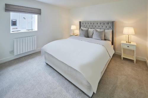 a white bedroom with a large bed and a window at Host & Stay - The Hay Loft in Wakefield