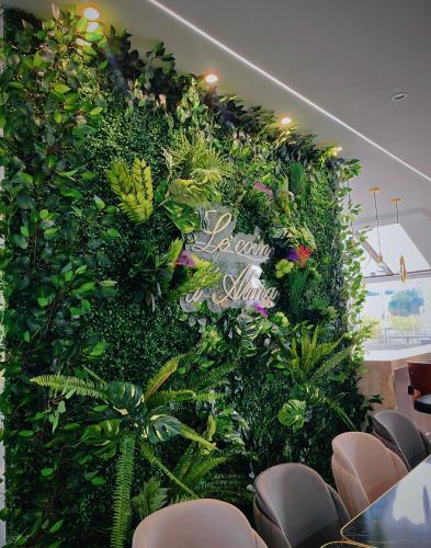 a green wall with plants in a room with chairs at Hôtel Restaurant Le Relais - Pau Nord in Lons