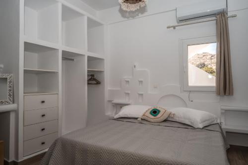 een witte slaapkamer met een bed en een raam bij ΚΑΤΟΙΚΙΑ ΜΕ ΜΙΝΙ ΠΙΣΙΝΑ ΣΤΗΝ ΠΑΡΑΛΙΑ 3 Larerooms 3 in Kithnos
