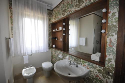 a bathroom with a sink and a toilet and a mirror at B&B Casa Soresina in Offagna