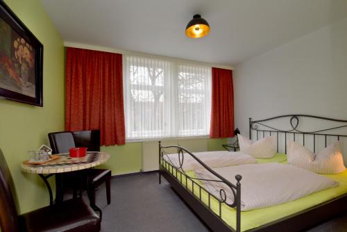 a bedroom with two beds and a table and a window at Hotel Goldene Sonne in Arnstadt