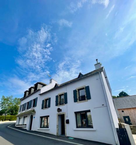 a white building with black windows on a street at Sur La Route Des Myrtilles in Gouézec