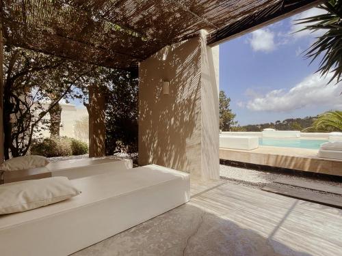 a white bedroom with a view of a swimming pool at Boutique Hotel Jardines de Palerm in San Jose