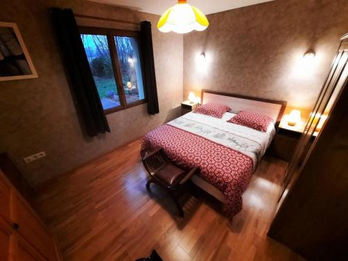 Schlafzimmer mit einem Bett mit roter Bettwäsche und einem Fenster in der Unterkunft L'appel de la foret in Rocroi
