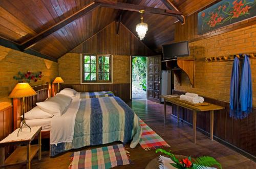 a bedroom with a bed and a tv in a room at Pousada do Rio Maua in Visconde De Maua